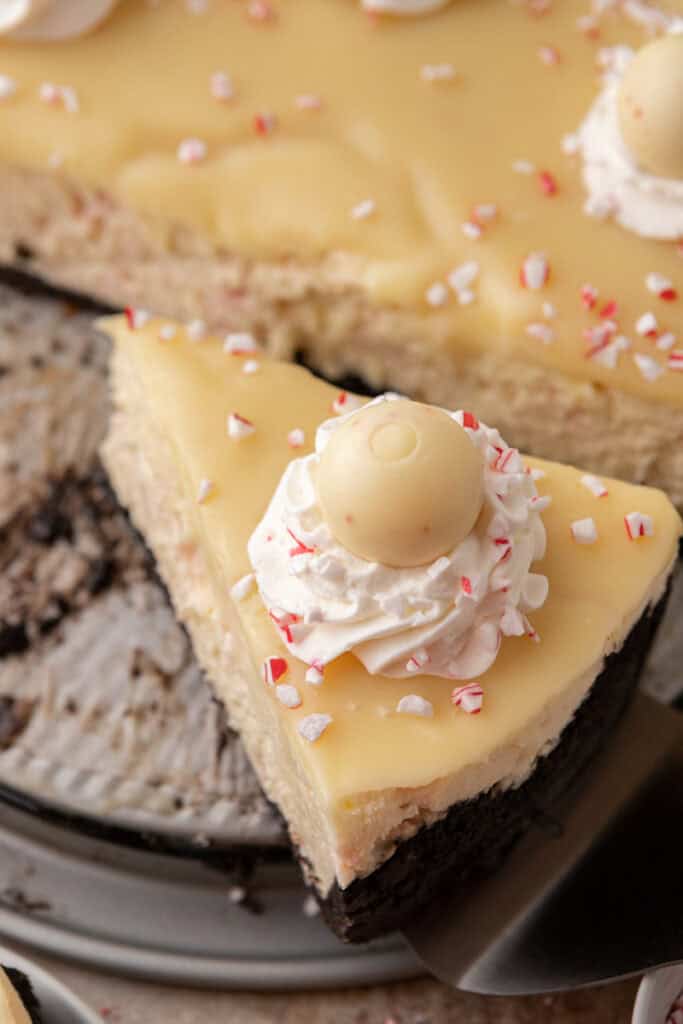 A slice of peppermint cheesecake being lifted from the pan, showing the Oreo crust and creamy filling.