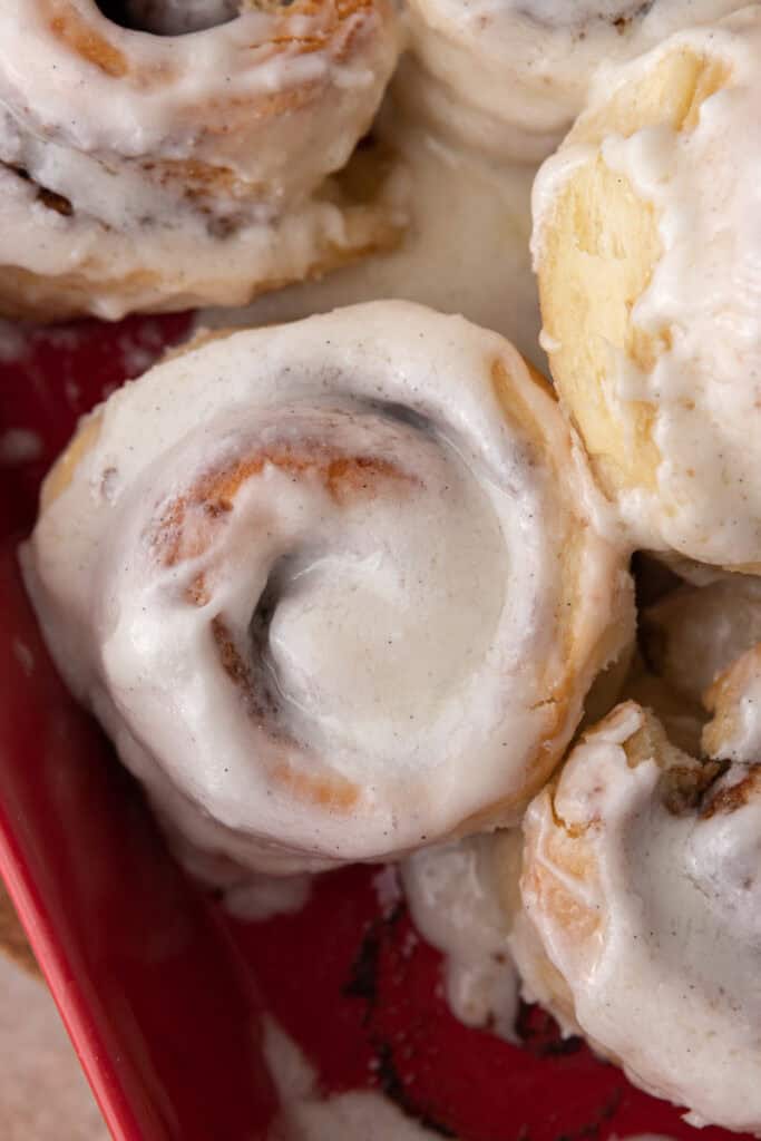 Soft homemade cinnamon rolls with frosting in a red baking dish