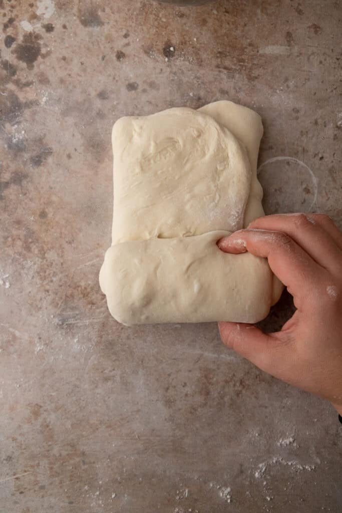 stretched out dough folded on a floured surface