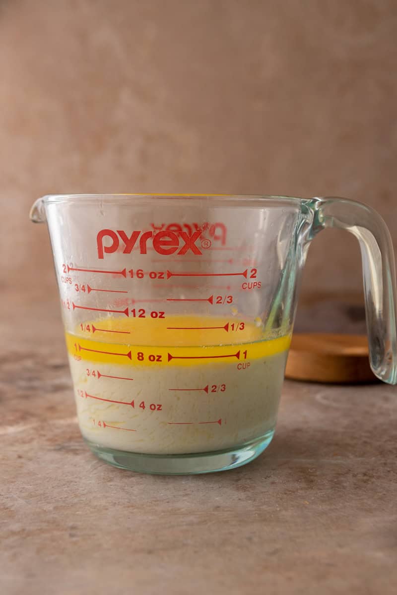 Melted butter poured over sourdough discard in a glass measuring cup.