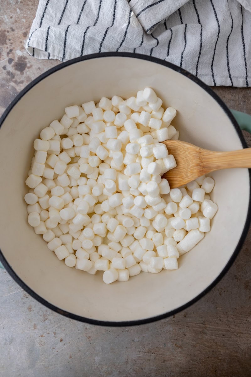 Mini marshmallows and butter in a white pot with a wooden spoon.