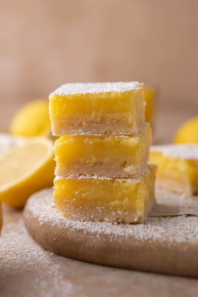 Classic lemon bars dusted with powdered sugar a popular easter dessert on a wooden board with fresh lemons