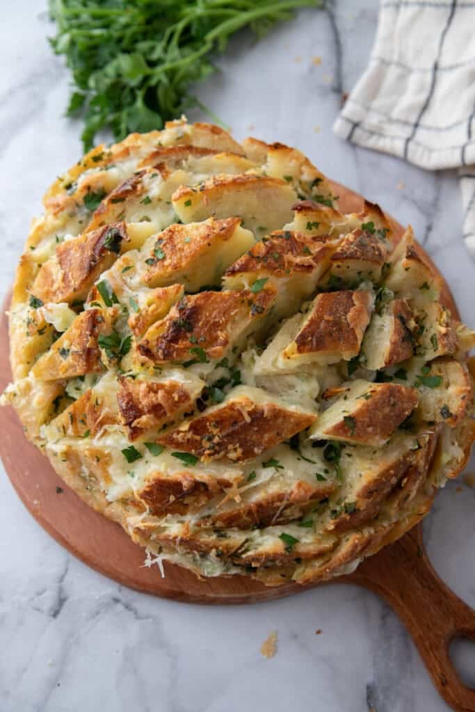 Golden baked garlic cheese bread served on wooden board