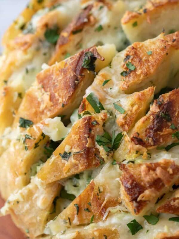Close-up of golden sourdough garlic bread baked with melted mozzarella and fresh parsley