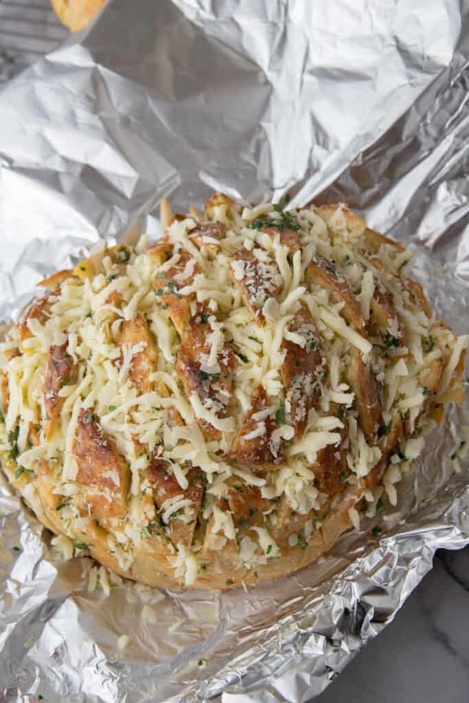 Unbaked sourdough garlic bread topped with shredded mozzarella and parmesan