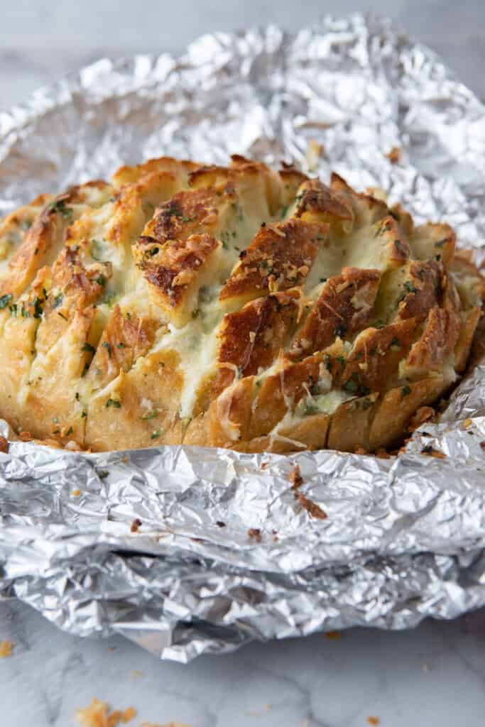 Freshly baked pull-apart garlic bread with melted cheese in foil