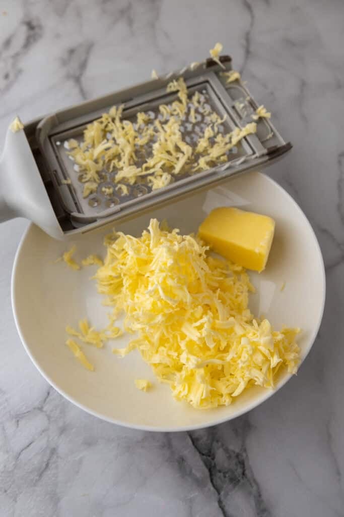 butter being grated into a bowl