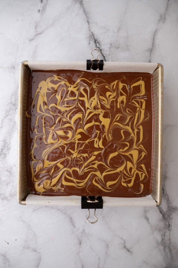 a finished dubai chocolate brownie in the pan showing swirls of chocolate and pistachio spread