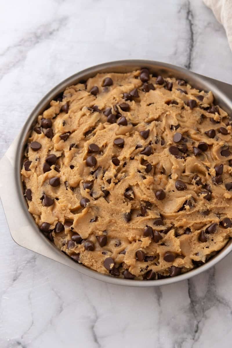 Chocolate chip cookie dough pressed into a round cake pan.