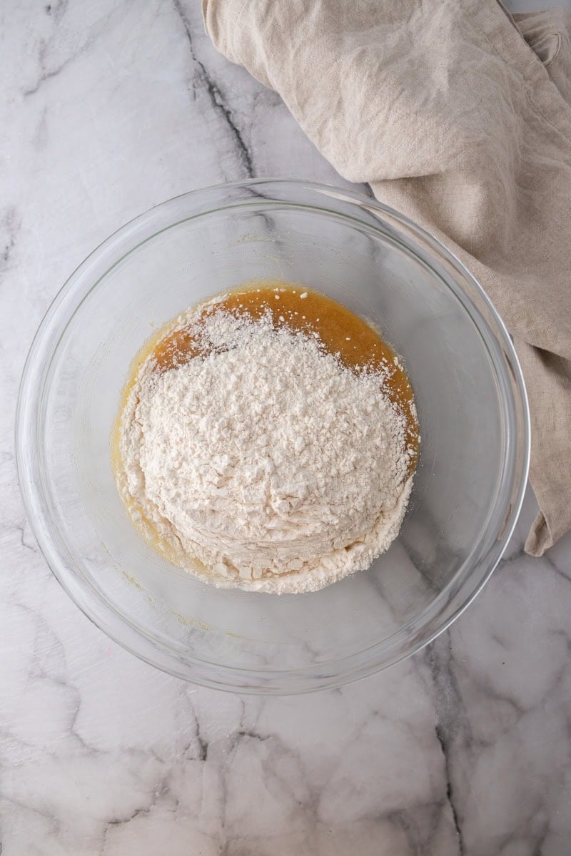 Flour added on top of the wet ingredients in a glass bowl.