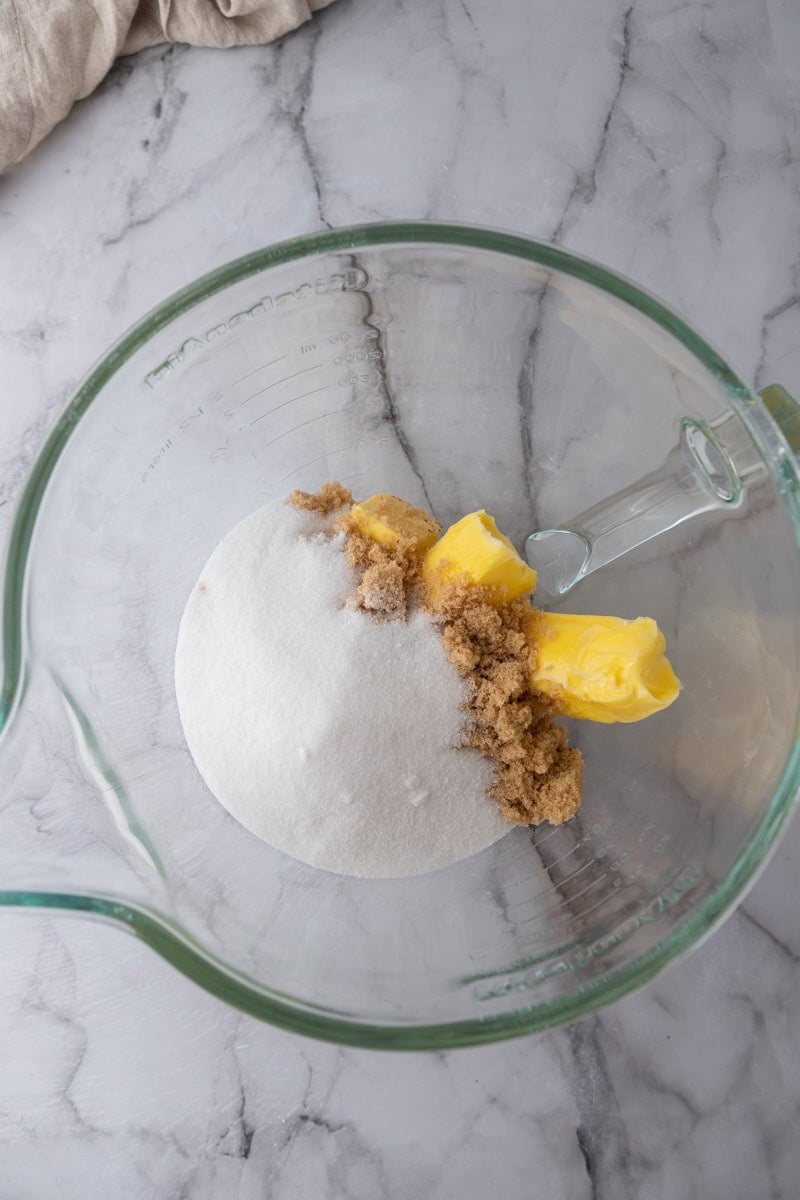 Granulated sugar, brown sugar, and butter in a glass stand mixer bowl.