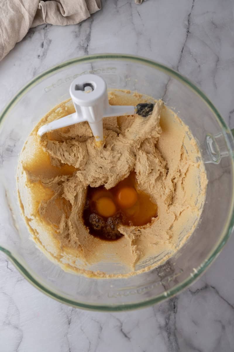 Eggs and vanilla added to the creamed butter and sugar in a stand mixer bowl.
