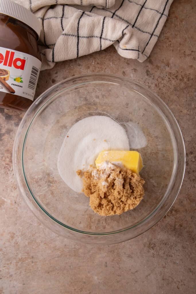 Ingredients for Nutella stuffed cookies including Nutella, butter, flour, egg, sugar, and chocolate chips