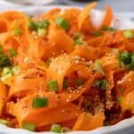 Carrot ribbon salad ready to serve, with dressing pooled lightly at the base of the bowl.