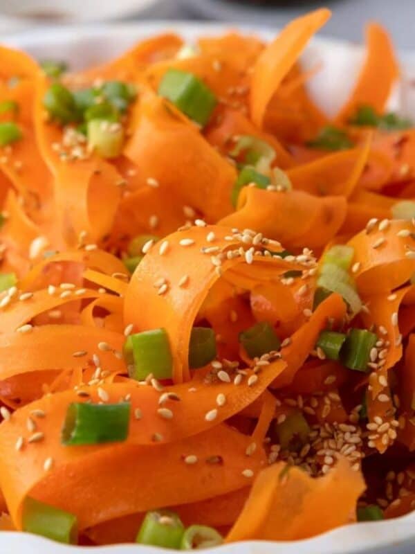Carrot ribbon salad ready to serve, with dressing pooled lightly at the base of the bowl.