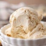 Two scoops of no-churn cream cheese ice cream in stacked white ribbed bowls.