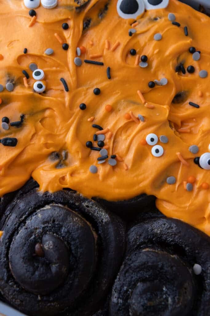 Black Cocoa Cinnamon Rolls being topped with icing