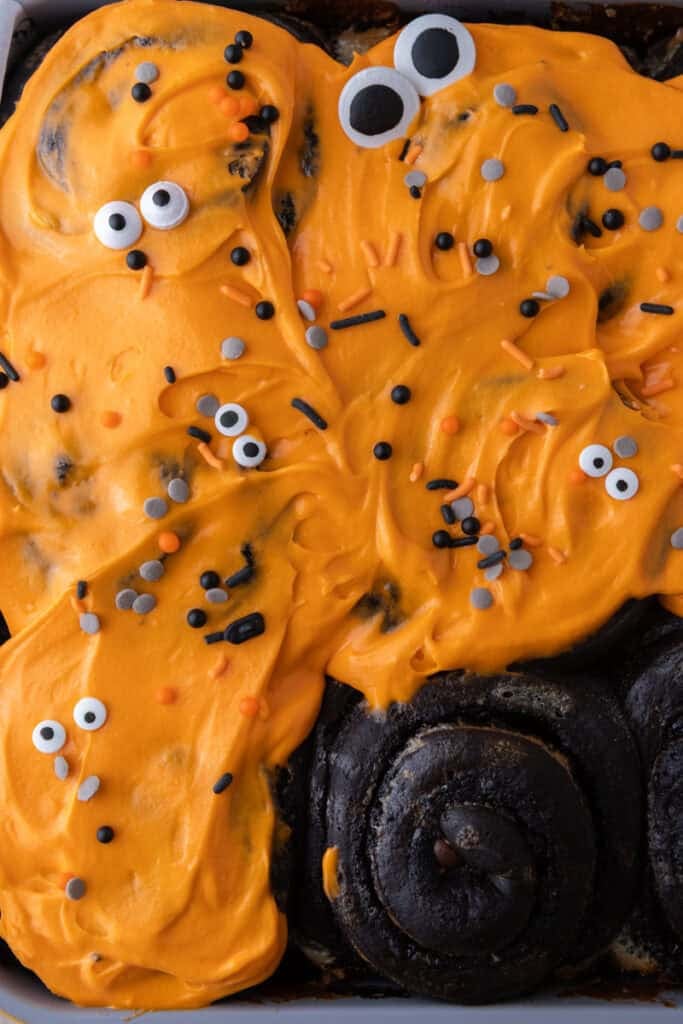 Black Cocoa Cinnamon Rolls being topped with icing