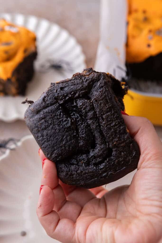 Black Cocoa Cinnamon Rolls being held up by a hand
