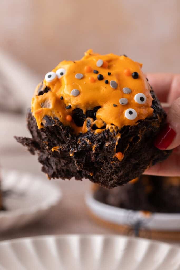 Black cocoa Halloween cinnamon roll with orange frosting and candy eyes