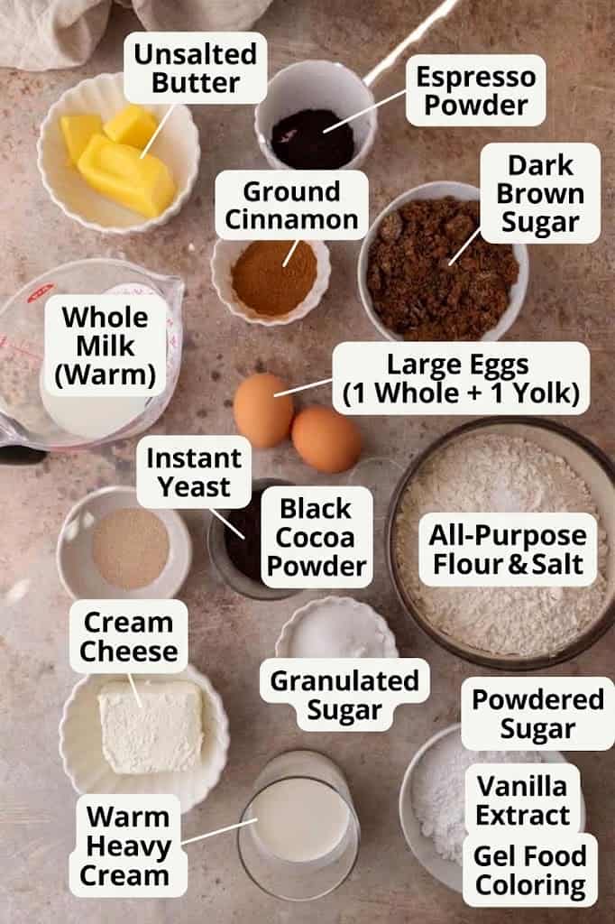 Labeled ingredients for black cinnamon rolls, including black cocoa powder, cream cheese, and warm milk.