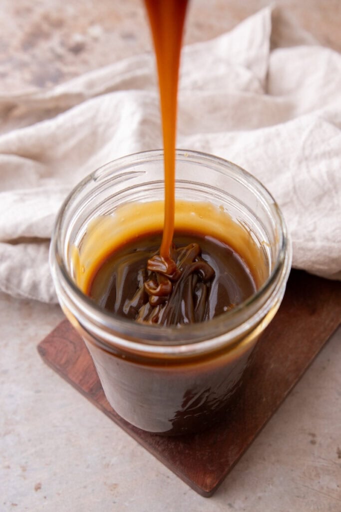 Butterscotch sauce in a jar with a spoon.
