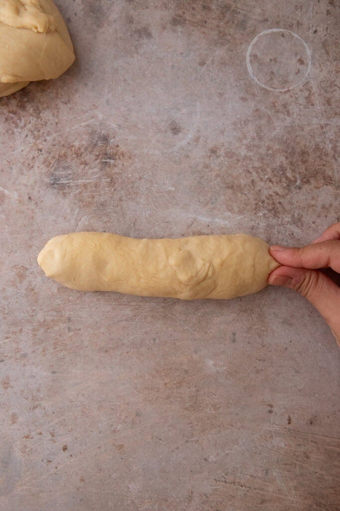 Pinching the seam of a shaped hoagie roll closed.