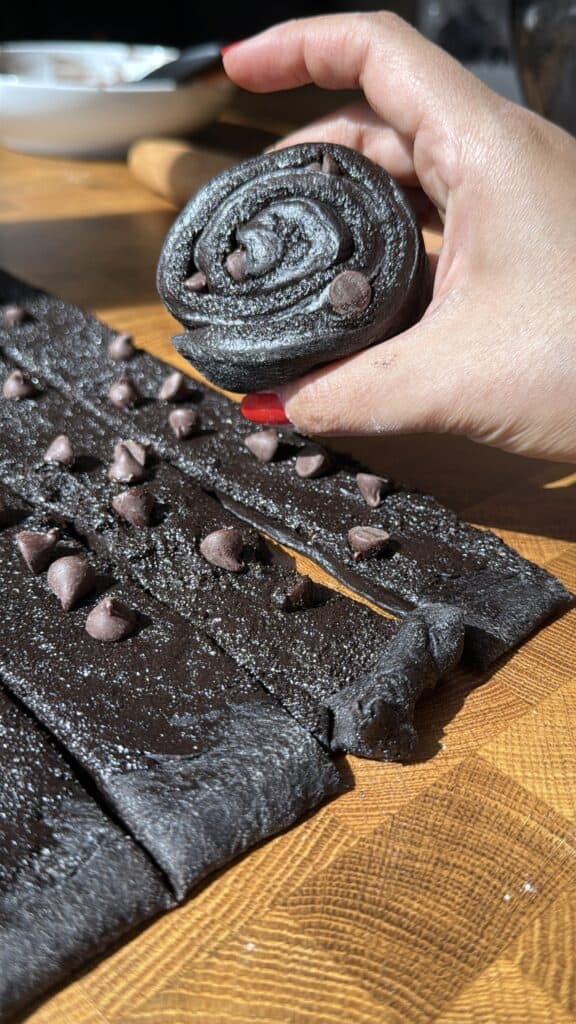 Hand holding black cocoa cinnamon roll