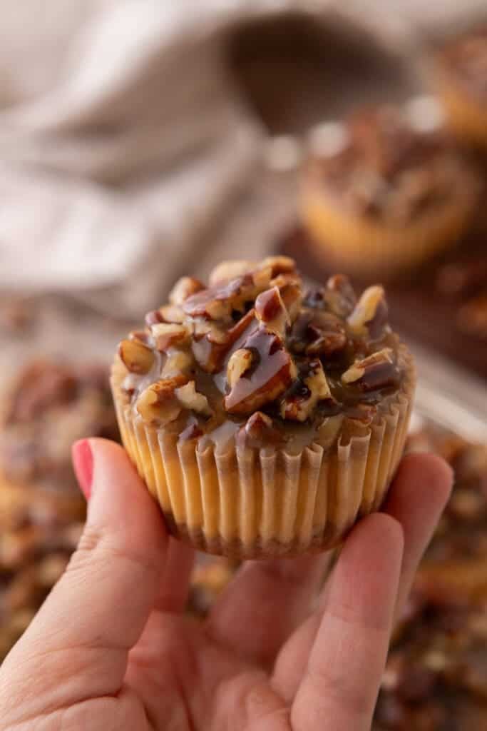Mini Pecan Pie Cheesecakes being held up by a hand