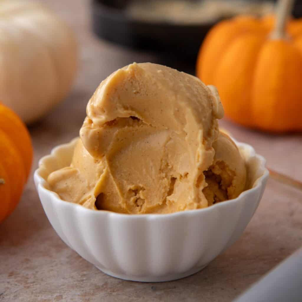 High-protein Ninja Creami pumpkin ice cream in white bowl with a bite taken out