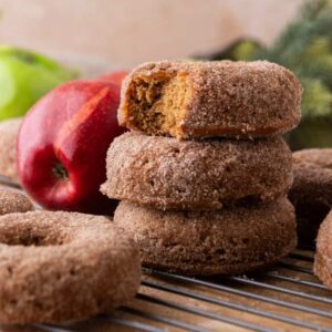 Fresh-baked apple cider donuts coated in cinnamon sugar, stacked with one donut showing a soft, fluffy inside.