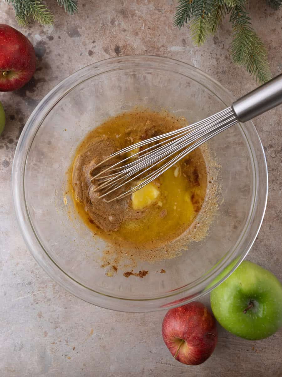 Whisking melted butter into sugar mixture while making baked apple cider donut batter.
