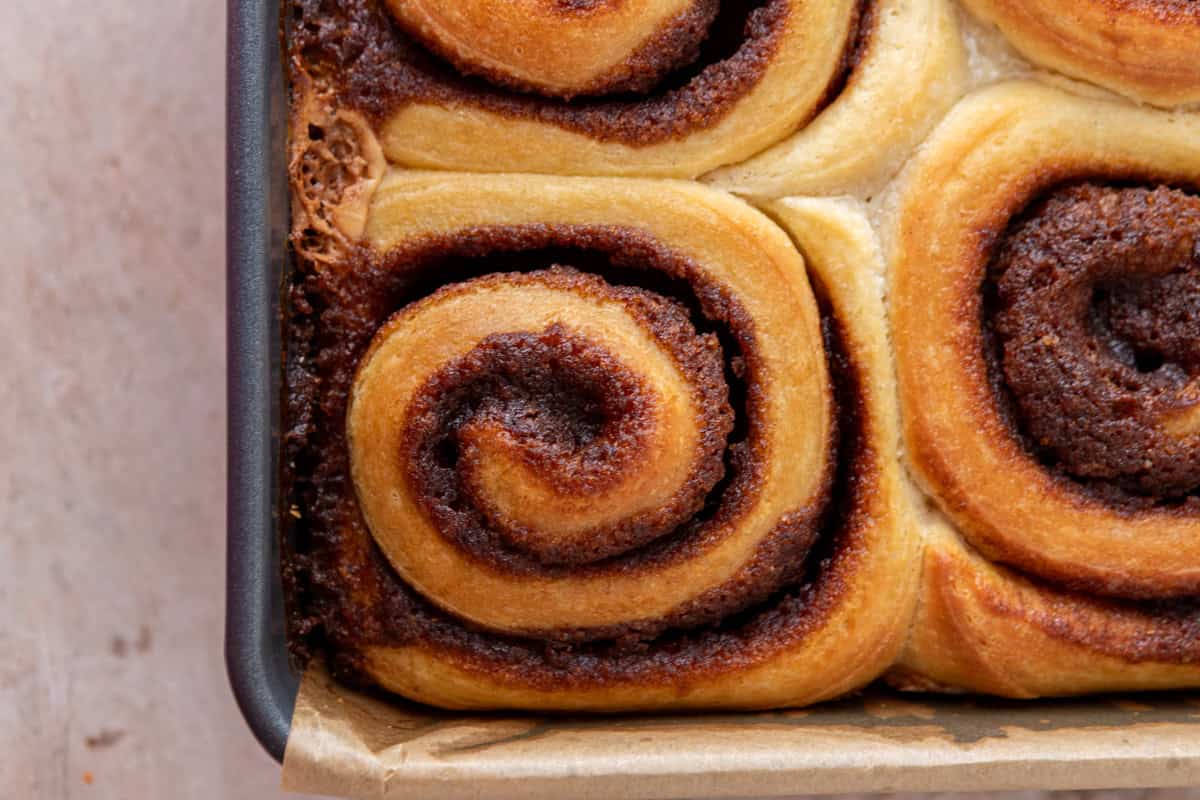 Golden baked cinnamon rolls with gooey swirls in pan