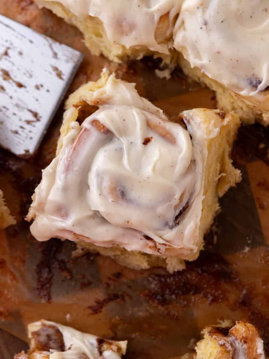 Gooey brioche cinnamon roll with cream cheese frosting lifted from a baking pa