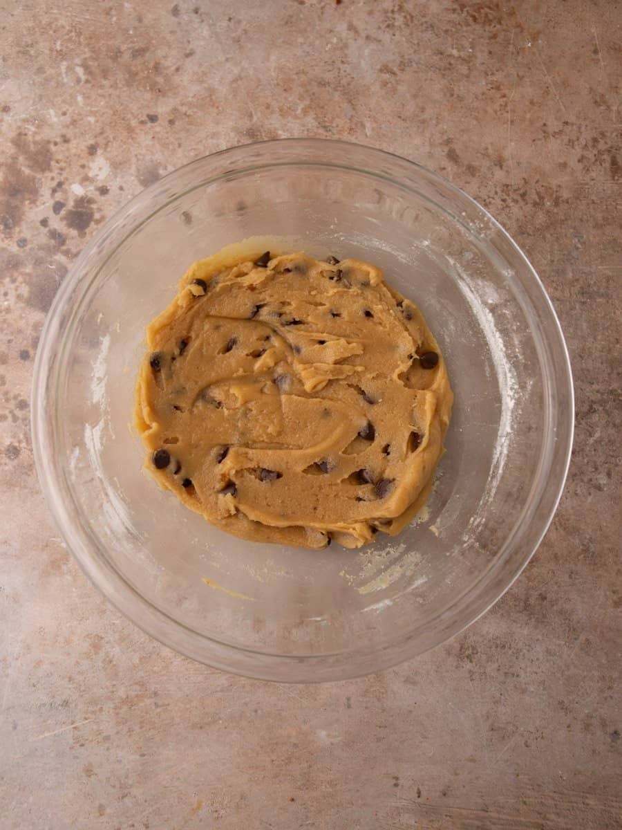 Smooth cookie dough mixed with chocolate chips ready to scoop.