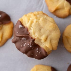 Close-up of a Danish butter cookie partially dipped in chocolate and sprinkled with flaky salt.