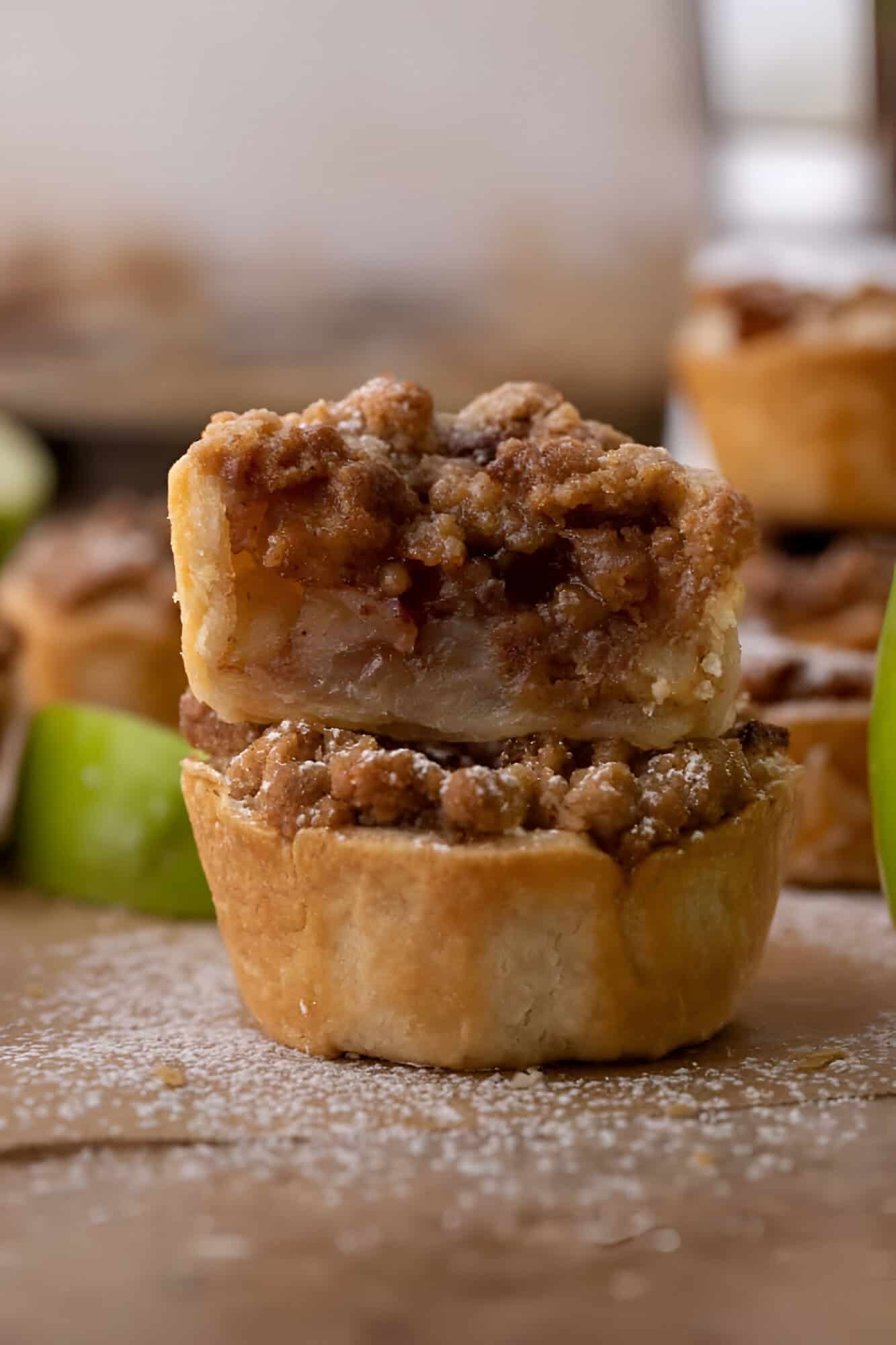 Mini apple pies topped with golden cinnamon streusel cooling on a wire rack.