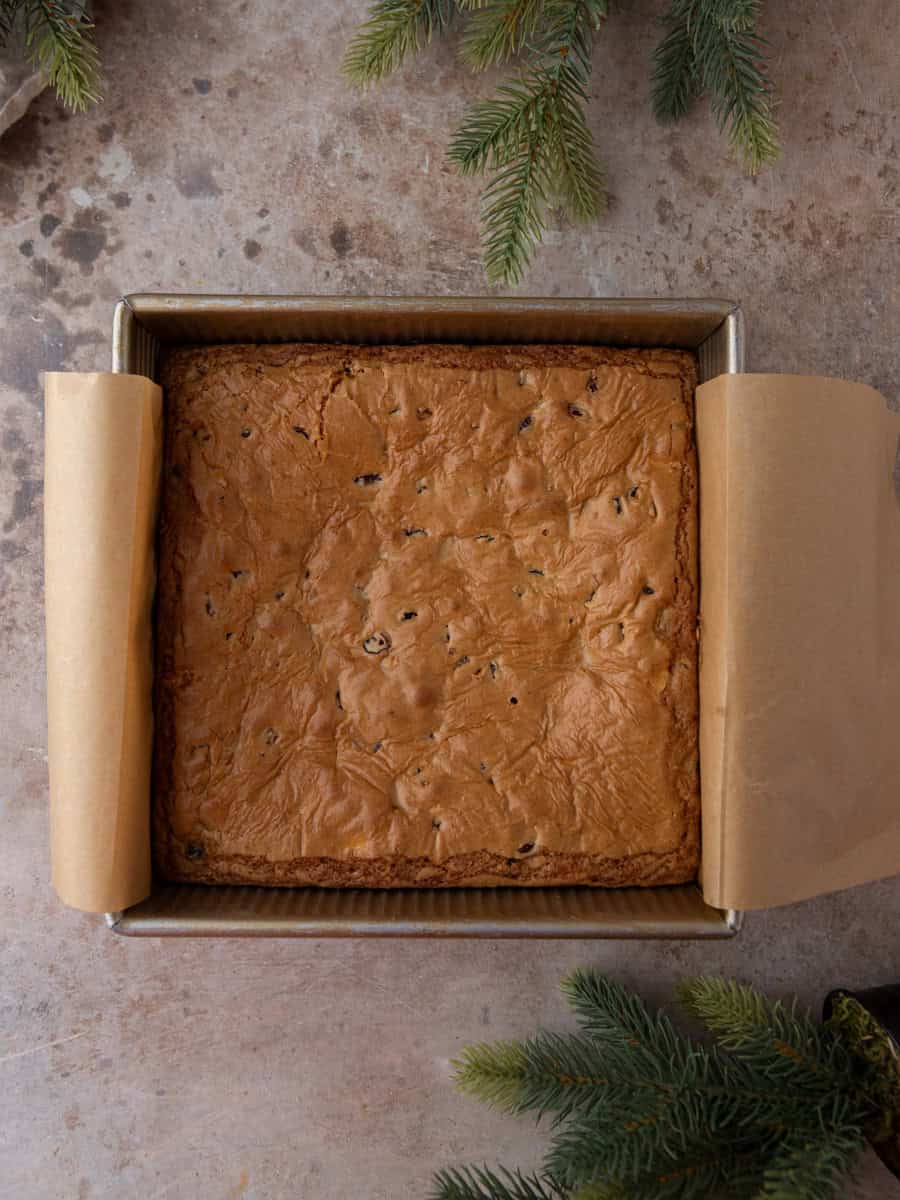 Freshly baked cranberry blondie slab cooling in a square parchment-lined pan.