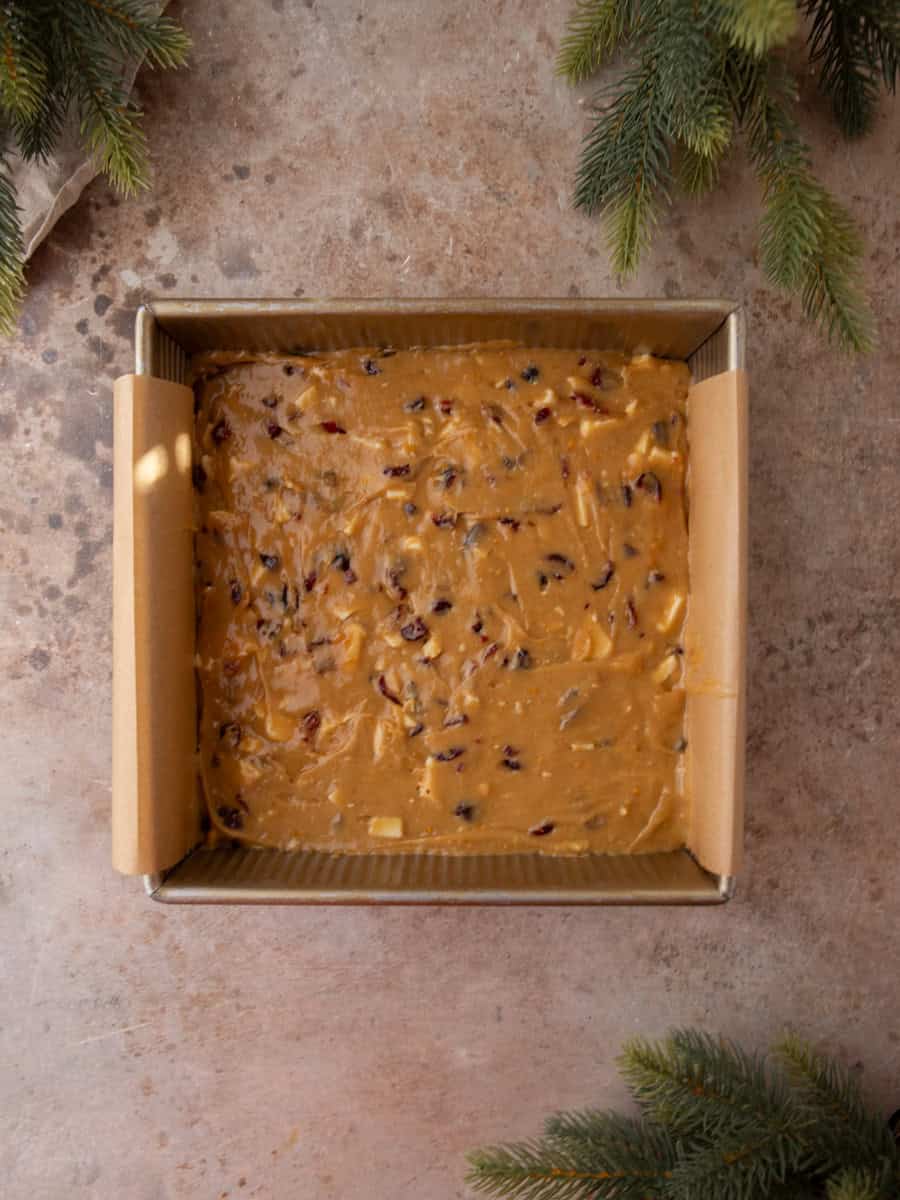 Cranberry blondie batter spread evenly in a parchment-lined square baking pan.