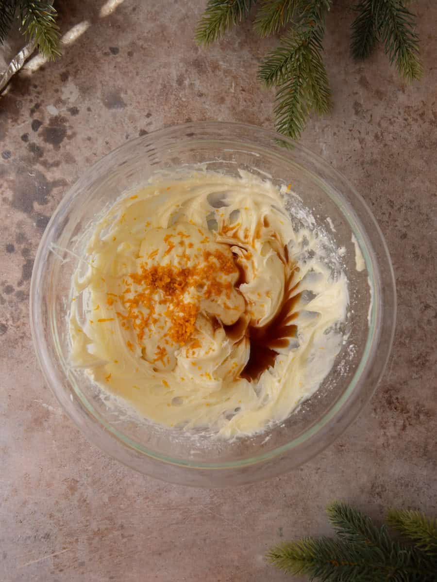 Cream cheese frosting in a bowl with fresh orange zest and vanilla added.
