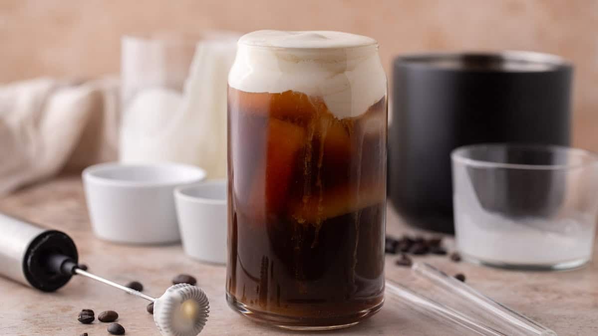 Iced cold brew in a glass topped with thick homemade protein cold foam, layered with creamy foam and coffee.