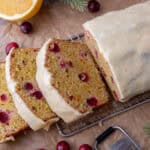 Sliced cranberry orange bread with orange glaze on a cooling rack