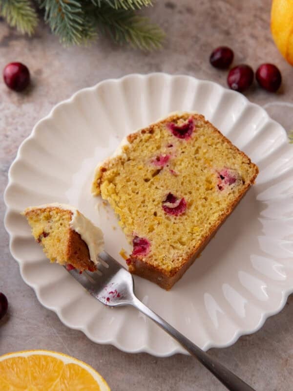 Slice of cranberry orange bread on a white plate with fork