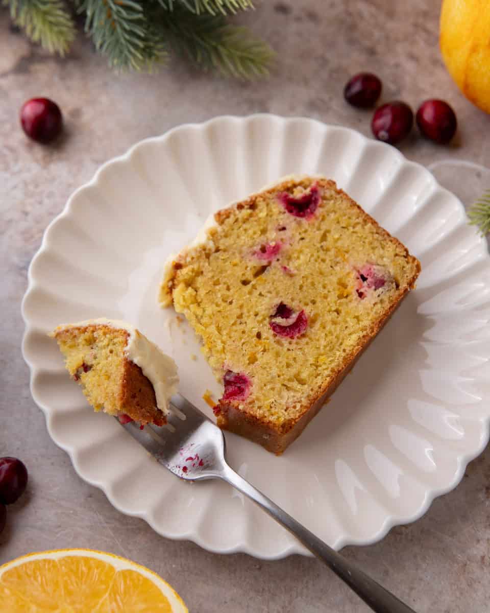 Slice of cranberry orange bread on a white plate with fork