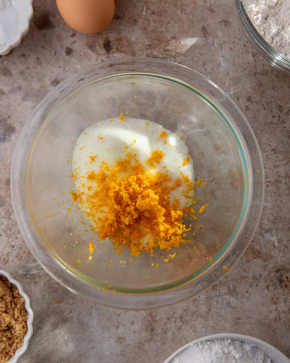 Granulated sugar mixed with fresh orange zest in bowl