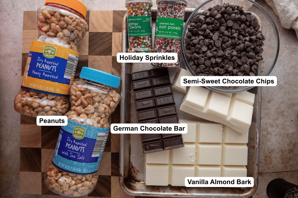 Crockpot candy ingredients: peanuts, vanilla almond bark, German chocolate, chocolate chips, and holiday sprinkles.