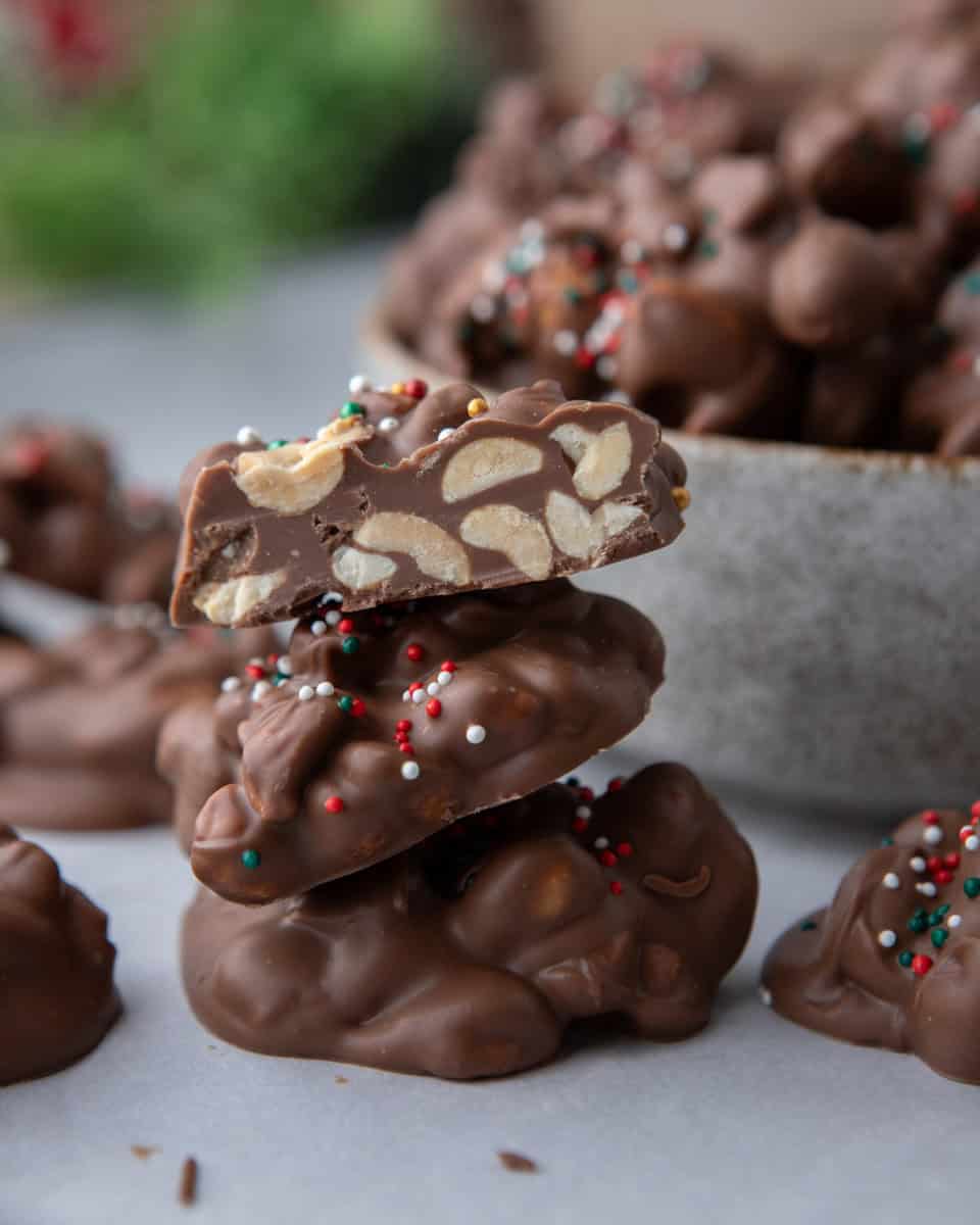 Stack of crockpot candy clusters with one cut open showing peanuts inside