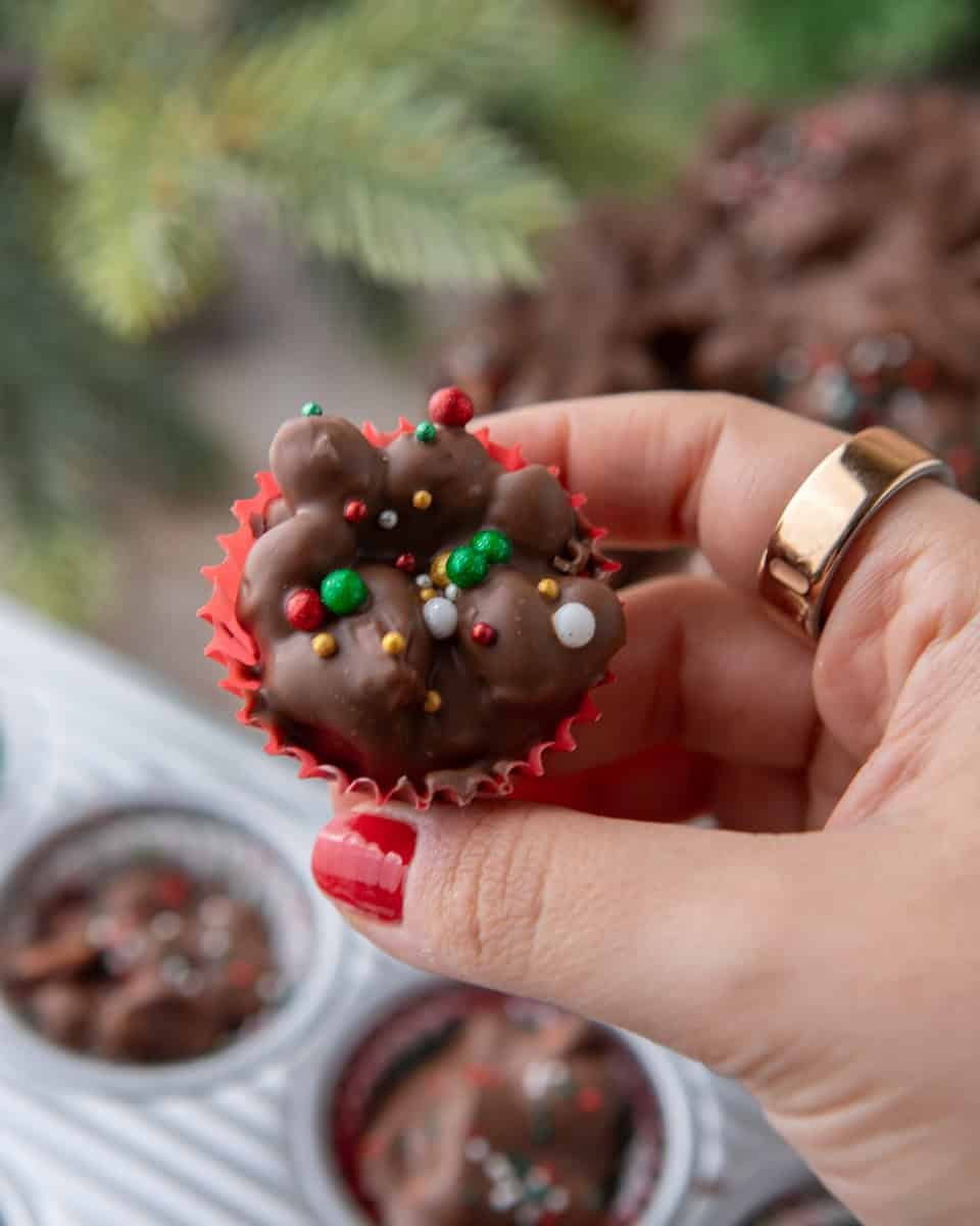 Hand holding a mini crockpot candy bite in a red cupcake liner with festive sprinkles