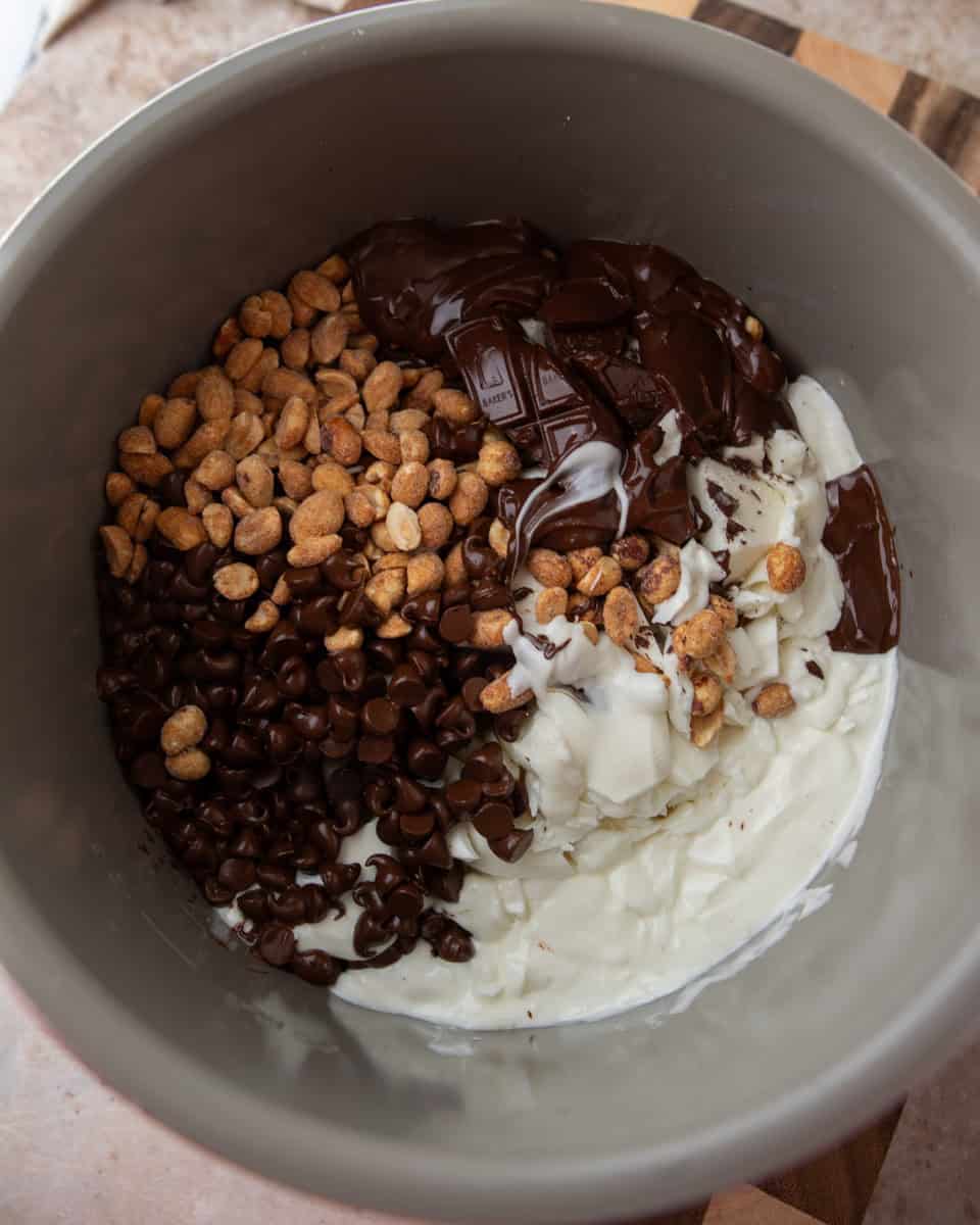Chocolate, peanuts, and almond bark layered inside a slow cooker before melting