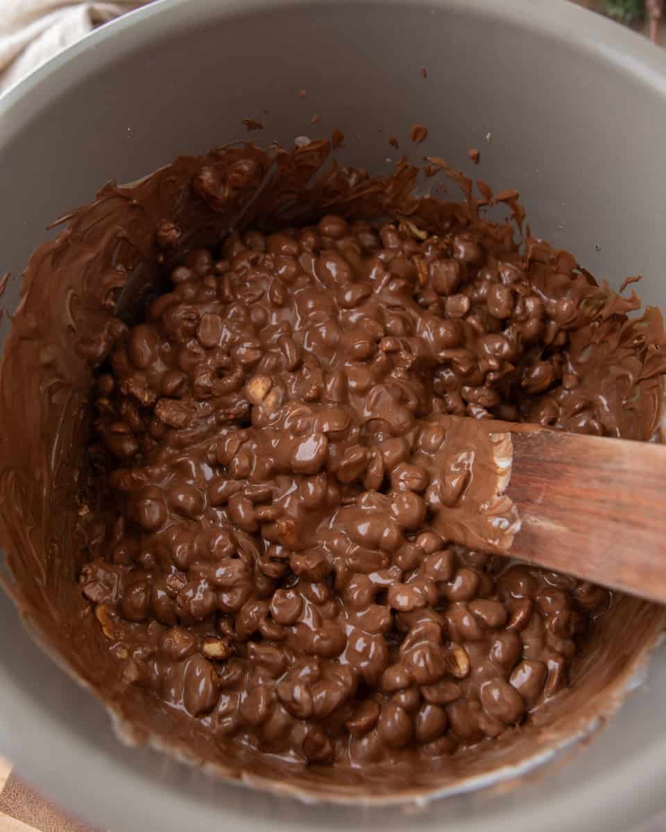 Melted chocolate and peanuts stirred together in a slow cooker.